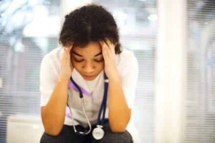 Smutný deprimovaný mladý africký americký zdravotní sestra sedí s frustrovaným výrazem ve tváři, pocit přemožený pracovní zátěží na klinice, etnický lékař pocit únavy po vyčerpávající směny — Stock obrázek