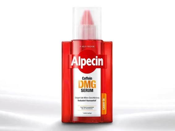 Eine rote Flasche Haarserum mit der Aufschrift "Alpecin Coffein DMG Serum" steht auf einer glatten, weißen Oberfläche.