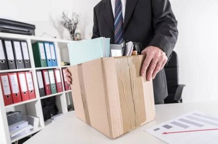 Businessman holding box with office items.