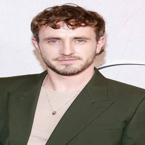 Person wearing a dark suit and light shirt at a GQ event backdrop
