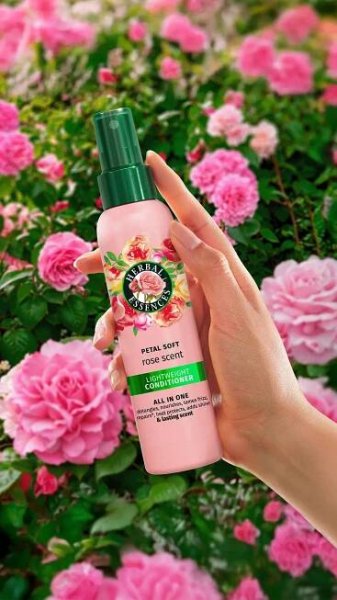 Hand holding pink spray bottle, surrounded by roses. 
Text: "HERBAL ESSENCES PETAL SOFT rose scent LIGHTWEIGHT CONDITIONER"