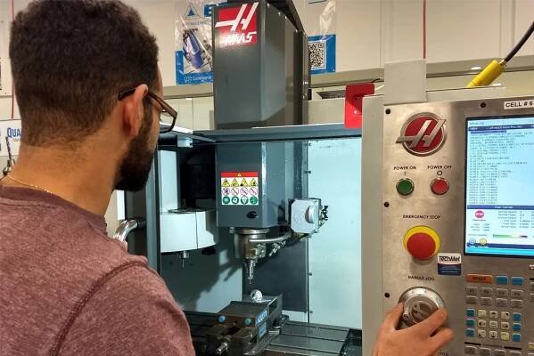 Person operating a Haas CNC machine, demonstrating practical skills in machining technology, relevant to CVCC's training programs for the manufacturing workforce.