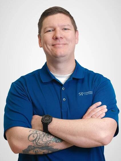 A man in a blue shirt is smiling for the camera