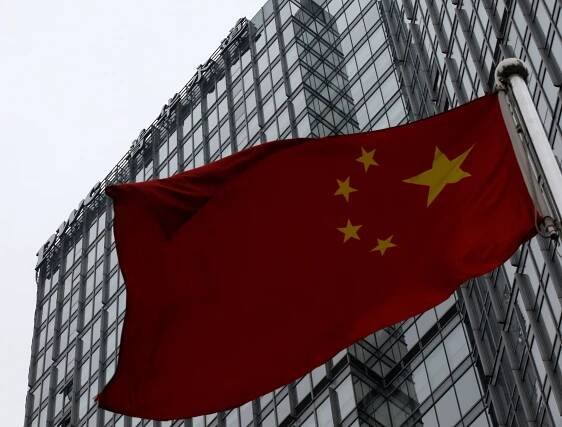 A building housing the PricewaterhouseCoopers (PWC) branch office stands behind a Chinese national flag in Beijing