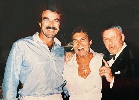 a photo of Tom Selleck and Larry Manetti of Magnum PI with the Chairman of the Board, Frank Sinatra, at Guido's. Sinatra holds one finger up.
