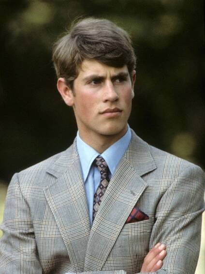 a young man in a suit and tie standing with his arms crossed looking at the camera