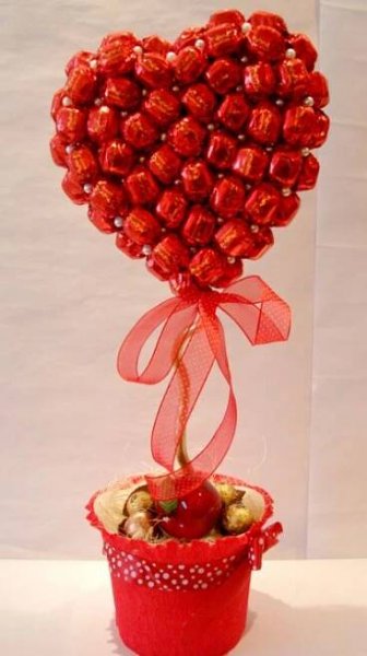 a heart shaped candy arrangement in a red bucket
