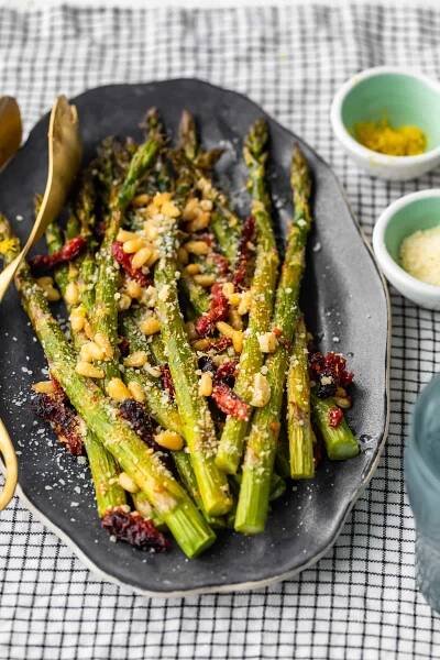 El espárrago asado al horno con tomates secados al sol, piñones, ajo y más es un delicioso plato de inspiración mediterránea para cualquier ocasión. ¡Esta receta fácil de espárragos asados ​​es rápida de preparar pero llena de sabor! Agregue esta guarnición de espárragos a sus comidas navideñas, o simplemente a sus cenas entre semana. De cualquier manera, ¡seguramente será un éxito!