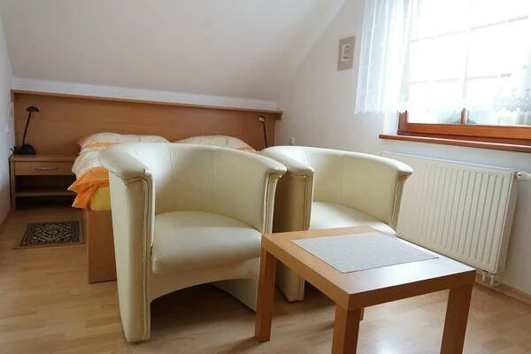two chairs and a table in a room with a bed at Penzion u lázní in Velké Losiny