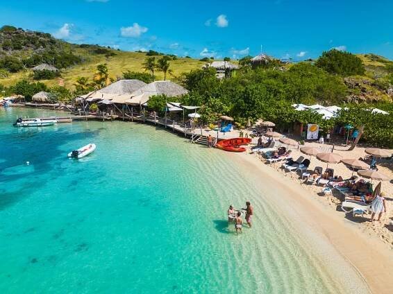 Karibuni beach restaurant on Pinel Island, St Martin, FWI. Beach chairs and umbrellas... by the clear water of the caribbean sea.