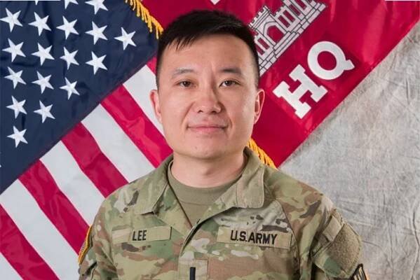 Joseph Lee in uniform stands in front of an American flag and a red military banner.