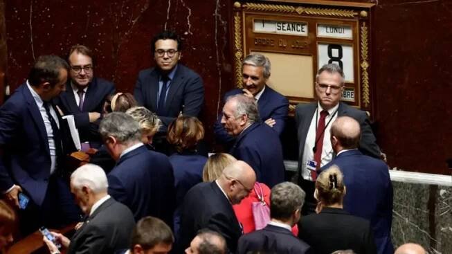 Prime Minister Francois Bayrou leaves National Assembly surrounded by lawmakers.