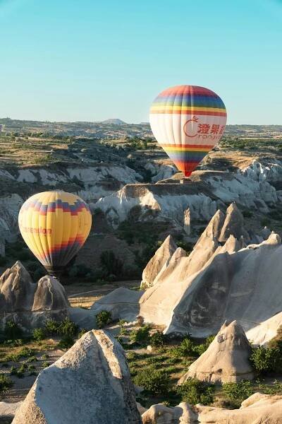 bezplatná Zářivé horkovzdušné balóny plující nad jedinečnými skalními útvary v Kappadokii při východu slunce. Základová fotografie