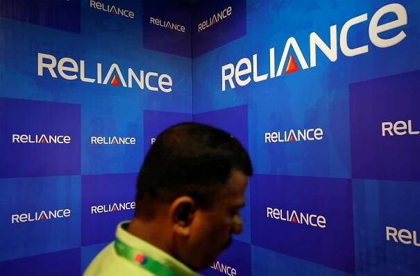A man walks past the logos of Reliance Anil Dhirubhai Ambani Group during the company's annual general meeting in Mumbai