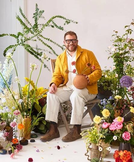 Matthew Ryan Muscarella seated amoung flower arrangements
