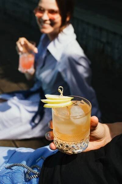 a person holding a drink with an apple slice on the rim
