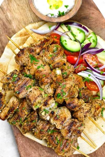 Souvlaki served on pita bread along with tomatoes and cucumber.