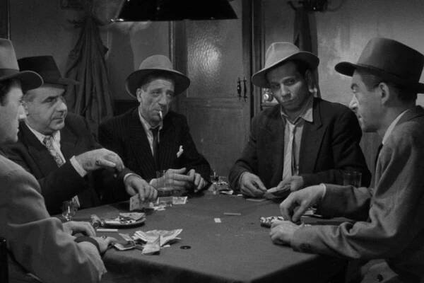 In this black and white still from Jules Dassin's RIFIFI, five men sit around a table, playing cards, drinking. One has a cigarette in his mouth. All wear fedoras, suit jackets, ties. They look at each other with suspicion.