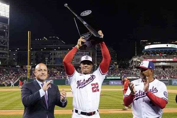 Nationals right fielder Juan Soto (22) holds the Silver Slugger trophy after he was presented with it before an Opening Day game against the Mets at Nationals Park, Thursday, April 7, 2022, in Washington. Looking on are general manager Mike Rizzo, left, and manager Dave Martinez.
