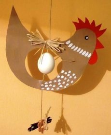 a mobile made to look like a fish hanging from a string on the wall with an egg in it's mouth