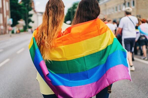 Zwei Freundinnen in eine LGBT+ Flagge gewickelt bei der Pride Parade.