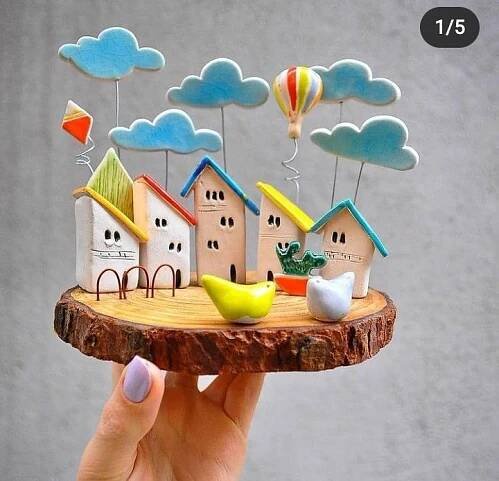 a hand holding a miniature model of houses and hot air balloons