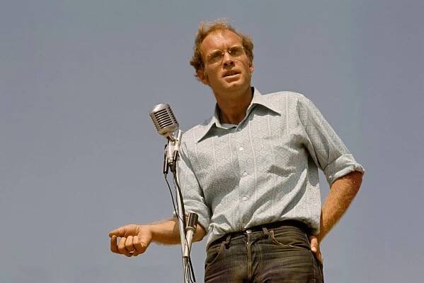 David Harris, a casually dressed young man with sandy hair and glasses, standing at a microphone.