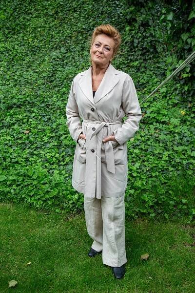 Herečka Simona Stašová nosí široké béžové kalhoty a béžový trenčkot.