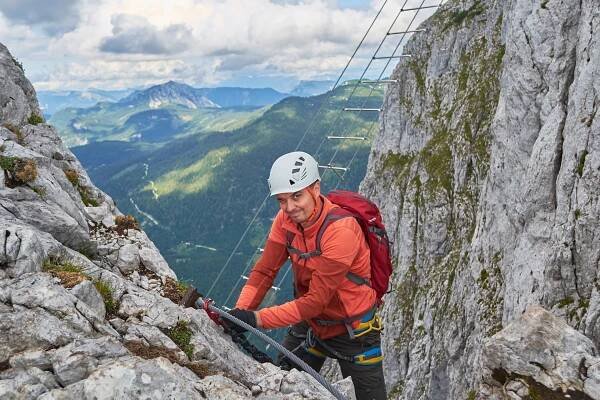 horolezec mrká směrem ke kameře, zatímco mění šňůry přes ferrata intersport, horu donnerkogel, rakousko. - dachstein - stock snímky, obrázky a fotky