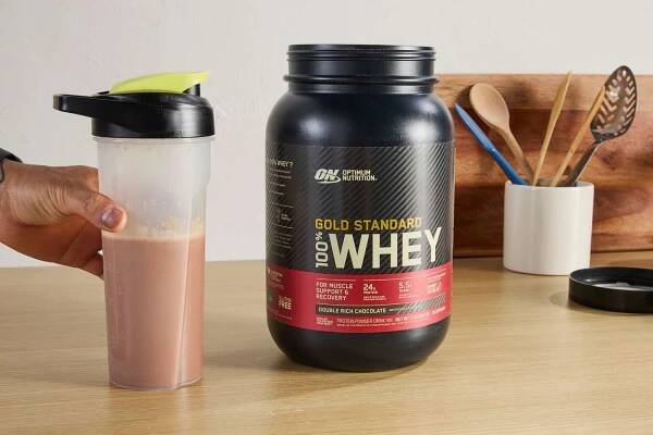 Person holding shake of Optimum Nutrition Gold Standard 100% Whey Protein Powder