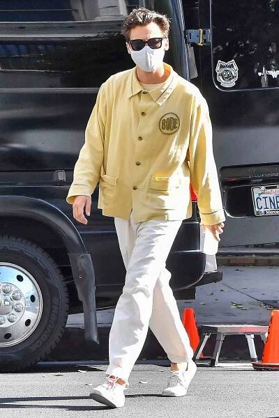 Harry Styles pulls off a pair of white pants and a yellow coat as he heads to set for Olivia Wilde's 
