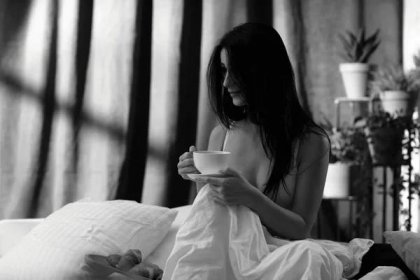 Krásná mladá žena pije její čaj ve své ložnici v dopoledních hodinách — Stock obrázek