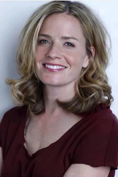 a woman with blonde hair smiling at the camera and wearing a red shirt, against a white background