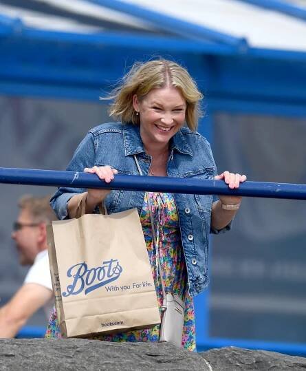 a woman holding a brown bag that says boots on it