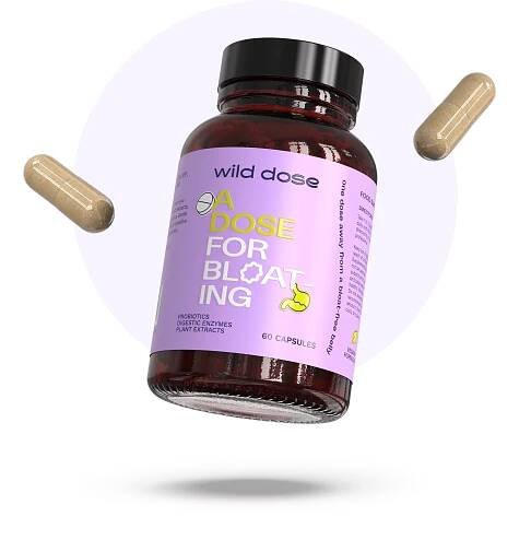 Bottle of Wild Dose bloating relief capsules with two loose capsules nearby.