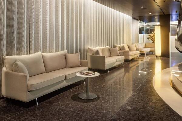 Melia Vienna Hotel Exterior photo The photo shows a modern and elegant waiting area. The walls are covered in vertical, light beige or cream-colored textured panels, creating a soft and inviting backdrop. The floor is made of dark, polished marble with subtle veining, reflecting the 