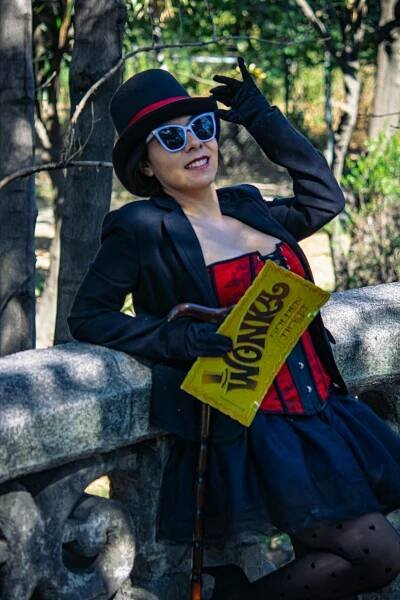 bezplatná Módní žena pózuje v parku v červeném korzetu, černé sukni a rekvizitě na vstupenky Wonka. Základová fotografie