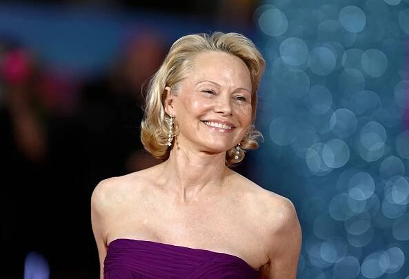 Person in strapless gown smiling at a public event