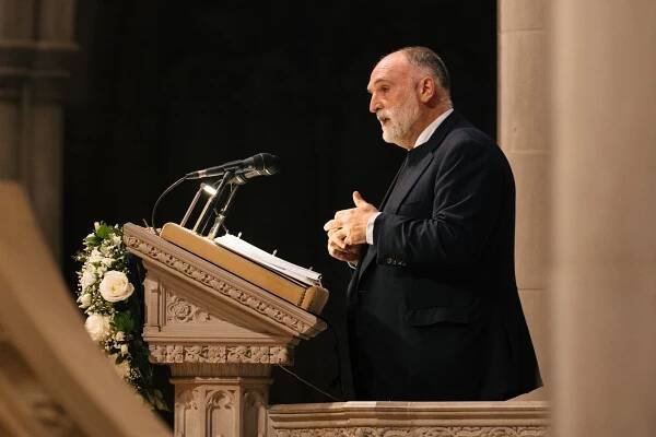 The chef Jose Andres, in a dark suit, stands at a lectern, speaking.