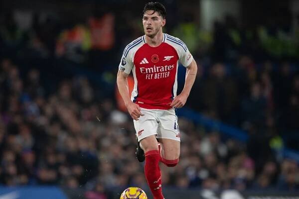 Declan Rice in a football uniform kicking a ball for Arsenal