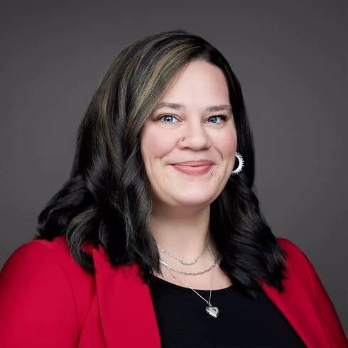 A woman wearing a red jacket and a heart necklace.