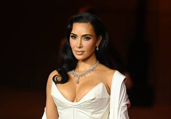Person in an elegant gown with a deep neckline and diamond necklace, posing at a formal event