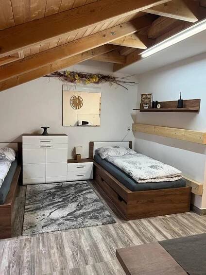 two beds in a room with wooden ceilings at Apartmány Nová duha Vavřinec in Vavřinec