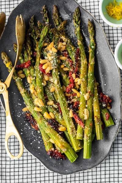 El espárrago asado al horno con tomates secados al sol, piñones, ajo y más es un delicioso plato de inspiración mediterránea para cualquier ocasión. ¡Esta receta fácil de espárragos asados ​​es rápida de preparar pero llena de sabor! Agregue esta guarnición de espárragos a sus comidas navideñas, o simplemente a sus cenas entre semana. De cualquier manera, ¡seguramente será un éxito!