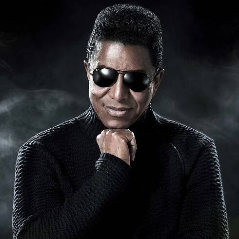 Portrait photo de Jermaine Jackson, posture affirmée et fond mystérieux.