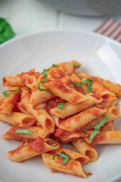 A closeup showing the tomato sauce on the pasta and fresh basil