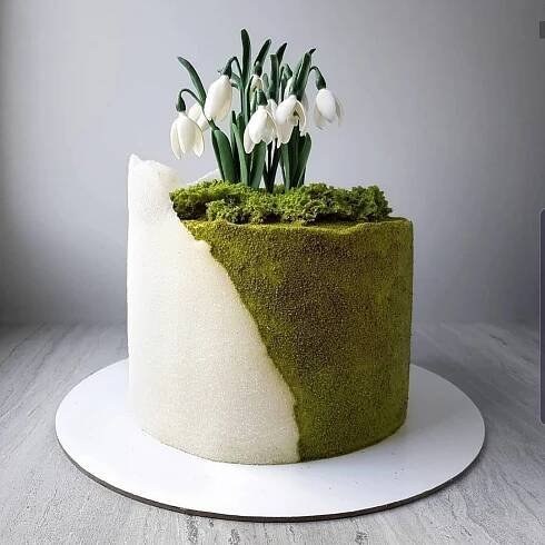 a moss covered cake with white flowers on top