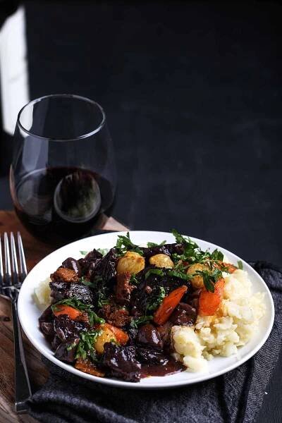 A warm, cozy serving of vegan bourguignon, packed with mushrooms, seitan, and herbs, garnished with fresh parsley for the perfect plant-based dinner.