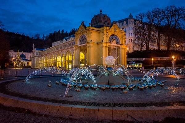 The Singing Fountain lit up at night in Winter, You can see the yellow Spa Colonnade behind it