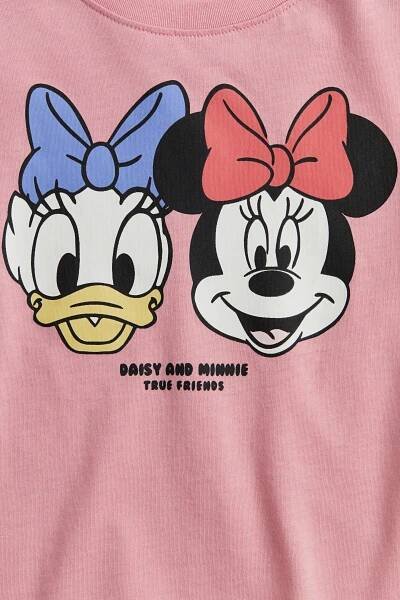 Zobrazit větší obrázek: Růžové tričko má na přední straně grafický potisk hlav Daisy Duck a Minnie Mouse. Tričko má také žebrovaný kulatý výstřih a pod postavami je natištěn text „DAISY AND MINNIE TRUE FRIENDS“.